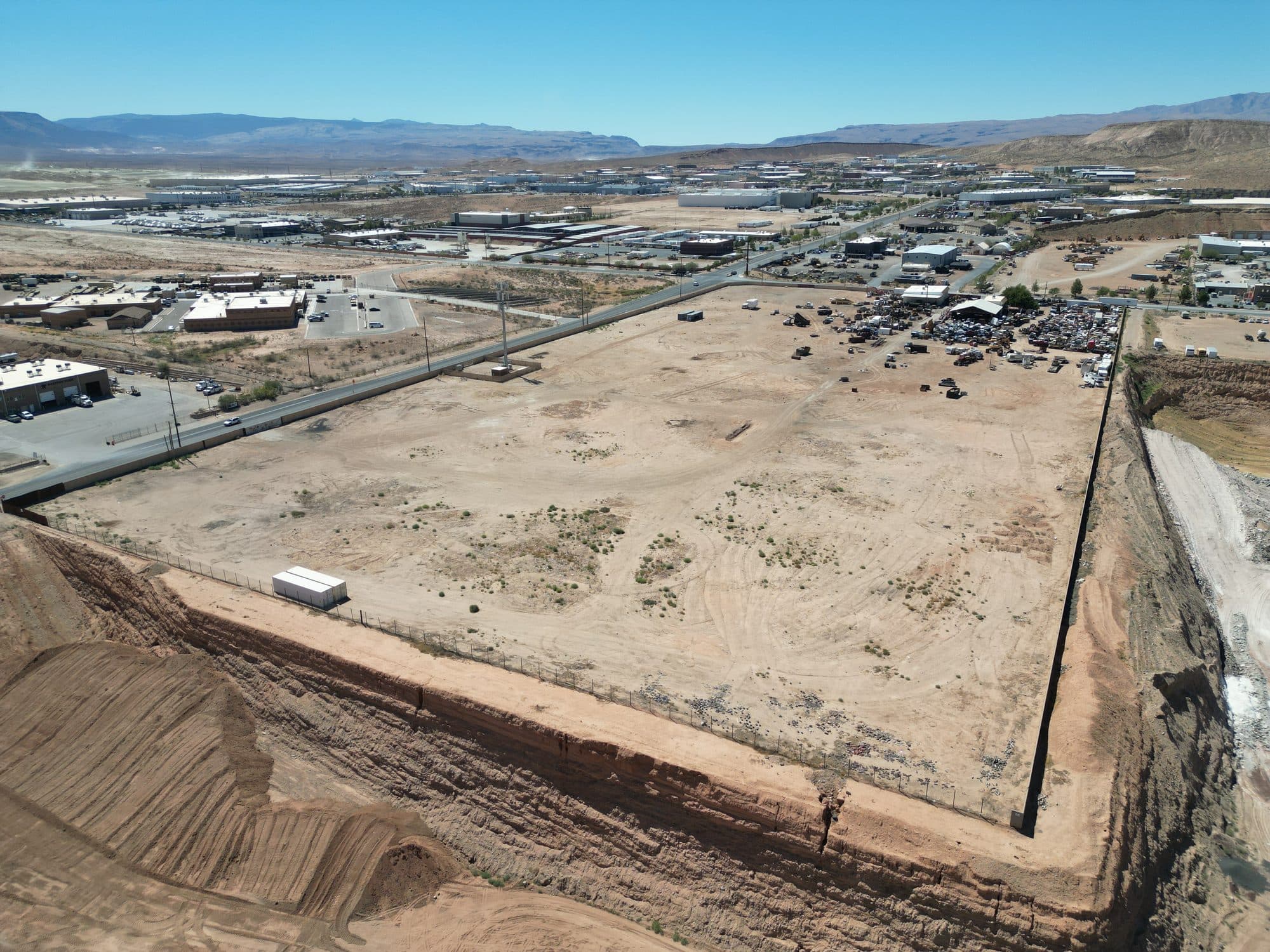 Aerial view of the cleared parcel and its perimeter berm, with existing industrial buildings beyond